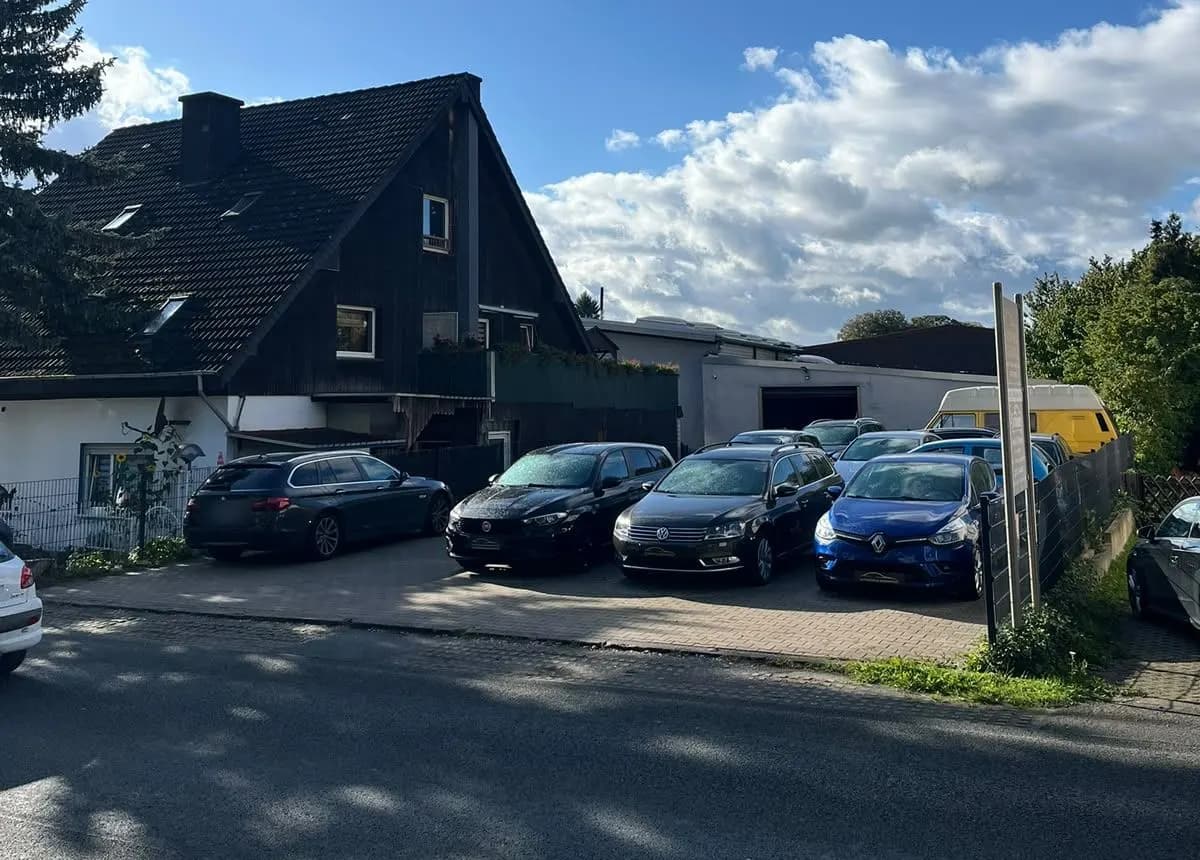 Unser Hof von der Straße aus mit Fahrzeugen und Halle im Hintergrund